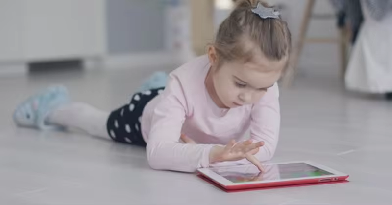 儿童使用平板电脑高清视频素材 Relaxing Girl Playing Tablet on Floor